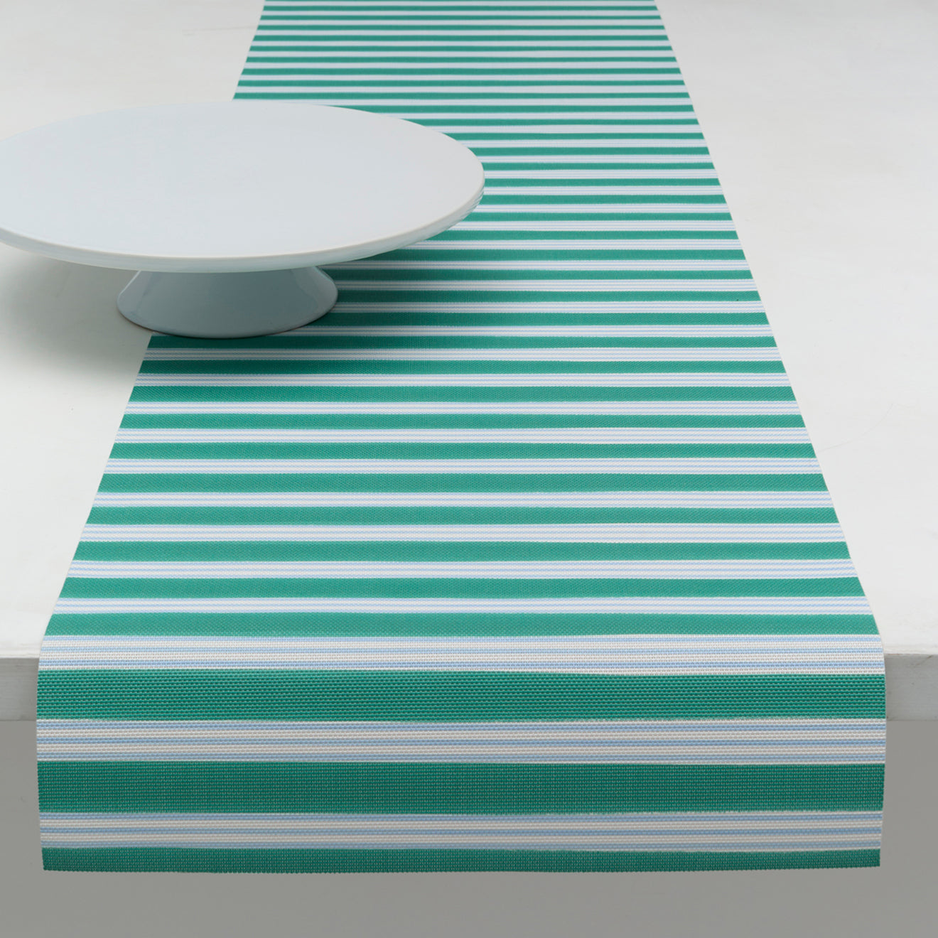 Chilewich striped woven mat with textured terrastrand yarn surface, featuring modern linear design and durable finish.