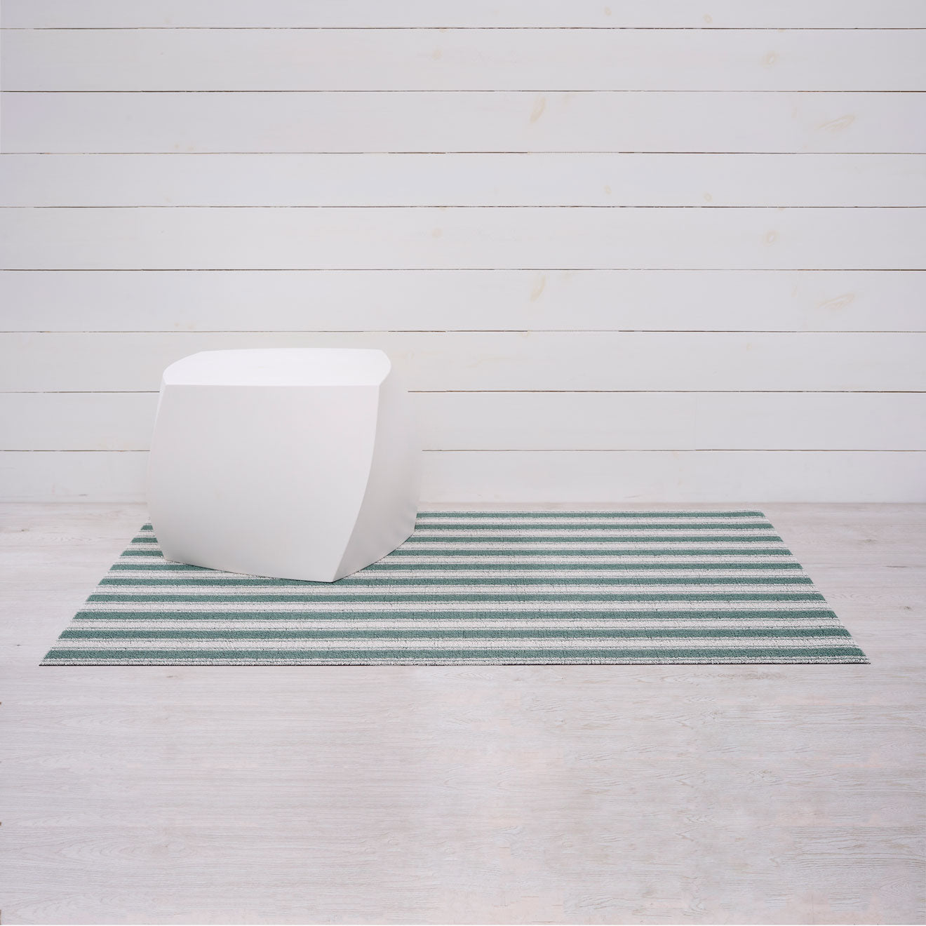 Chilewich striped woven mat with textured terrastrand yarn surface, featuring modern linear design and durable finish.