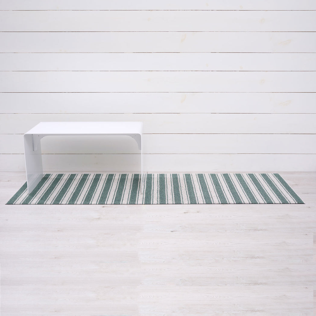 Chilewich striped woven mat with textured terrastrand yarn surface, featuring modern linear design and durable finish.