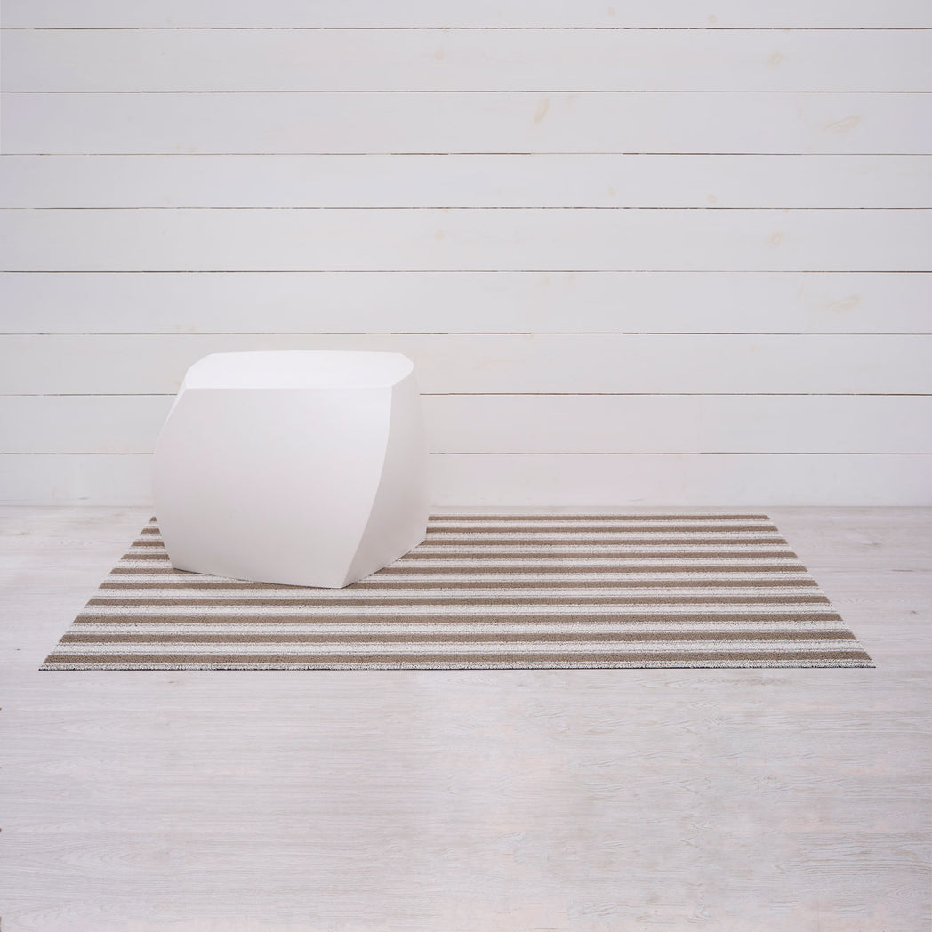 Chilewich striped woven mat with textured terrastrand yarn surface, featuring modern linear design and durable finish.