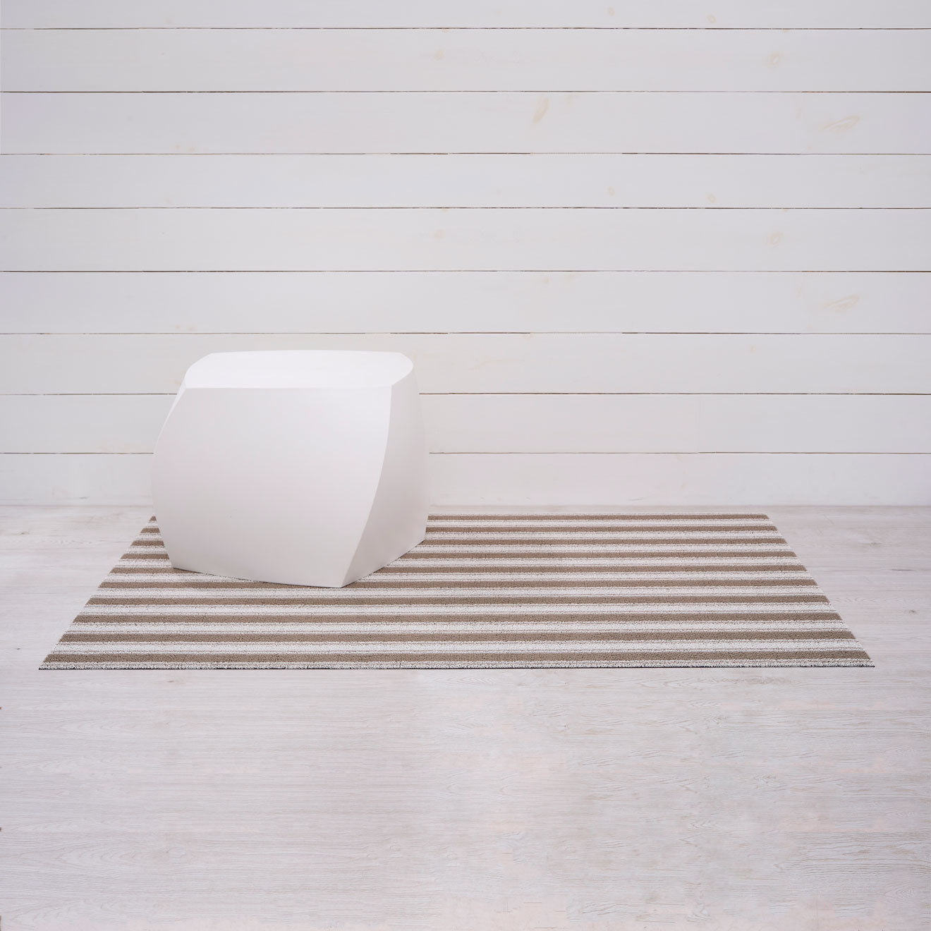 Chilewich striped woven mat with textured terrastrand yarn surface, featuring modern linear design and durable finish.