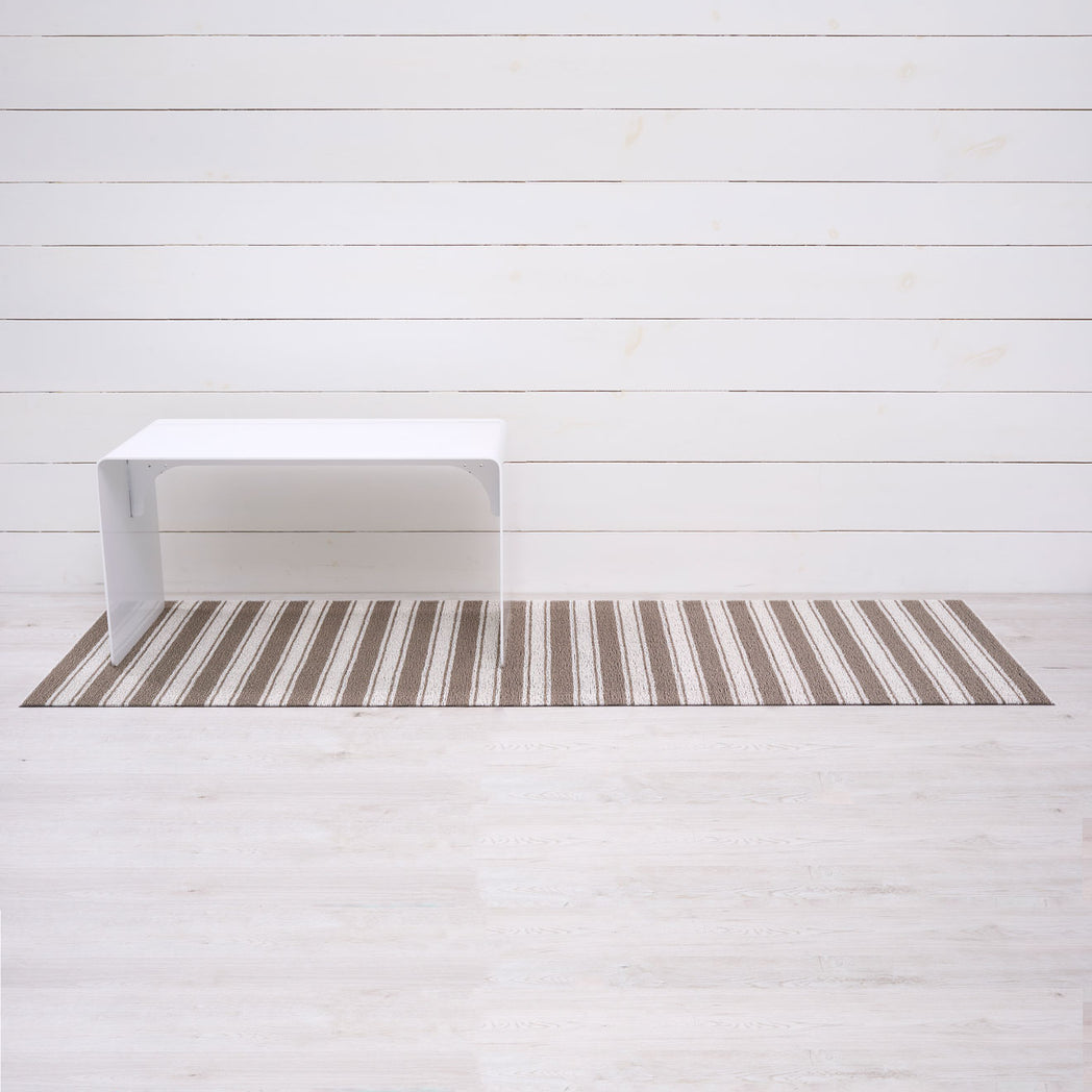 Chilewich striped woven mat with textured terrastrand yarn surface, featuring modern linear design and durable finish.