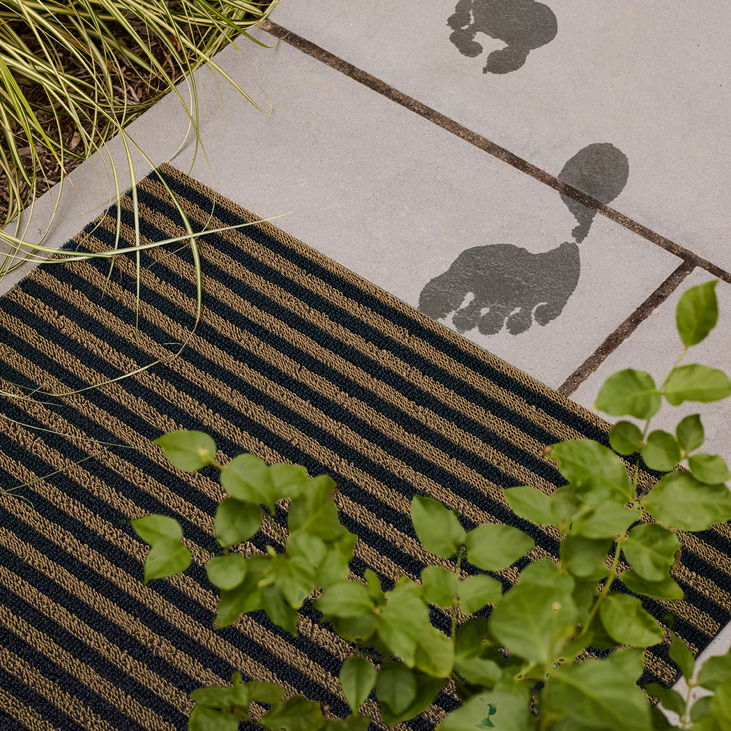 Chilewich striped woven mat with textured terrastrand yarn surface, featuring modern linear design and durable finish.