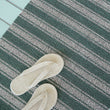 Chilewich striped woven mat with textured terrastrand yarn surface, featuring modern linear design and durable finish.