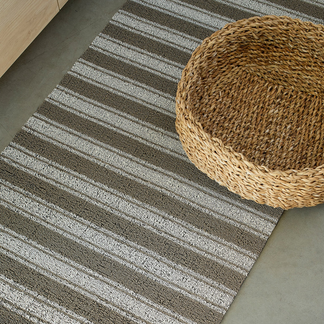 Chilewich striped woven mat with textured terrastrand yarn surface, featuring modern linear design and durable finish.