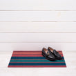 Chilewich striped woven mat with textured terrastrand yarn surface, featuring modern linear design and durable finish.