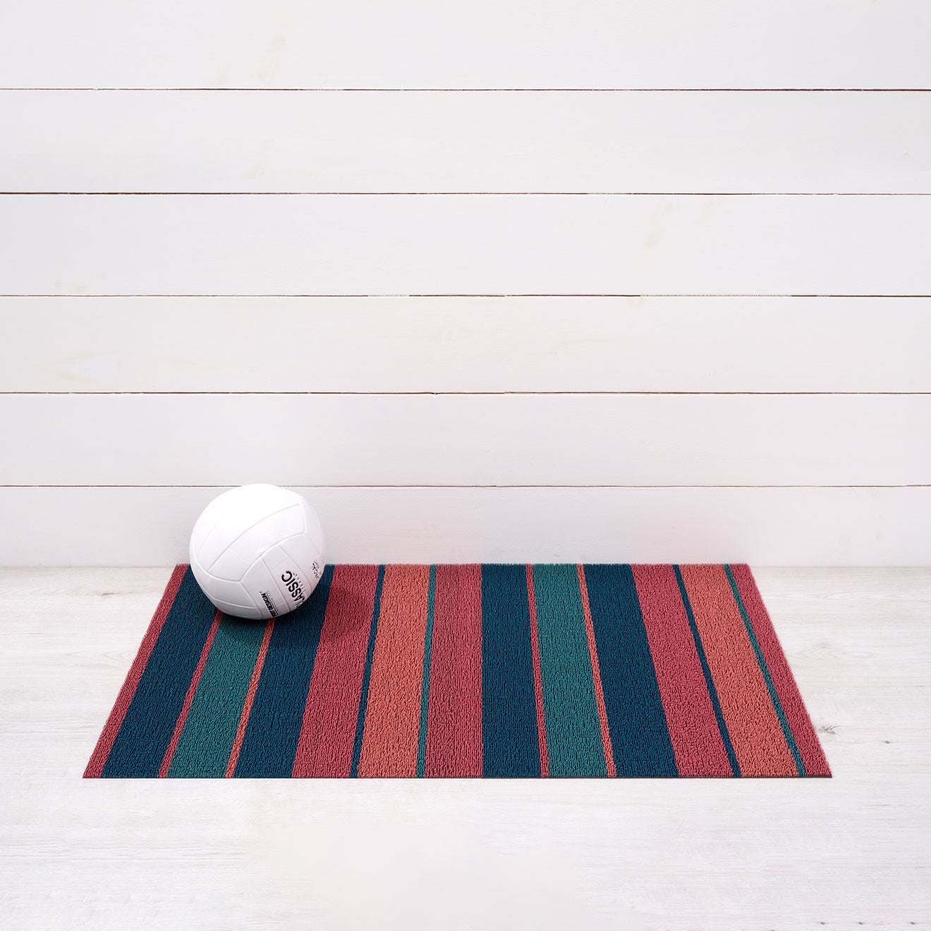Chilewich striped woven mat with textured terrastrand yarn surface, featuring modern linear design and durable finish.