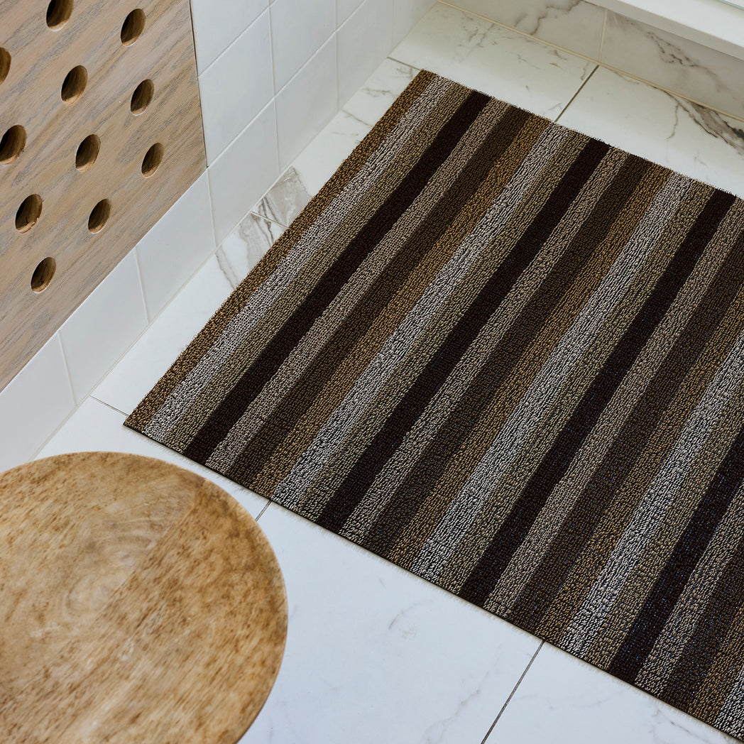 Chilewich striped woven mat with textured terrastrand yarn surface, featuring modern linear design and durable finish.