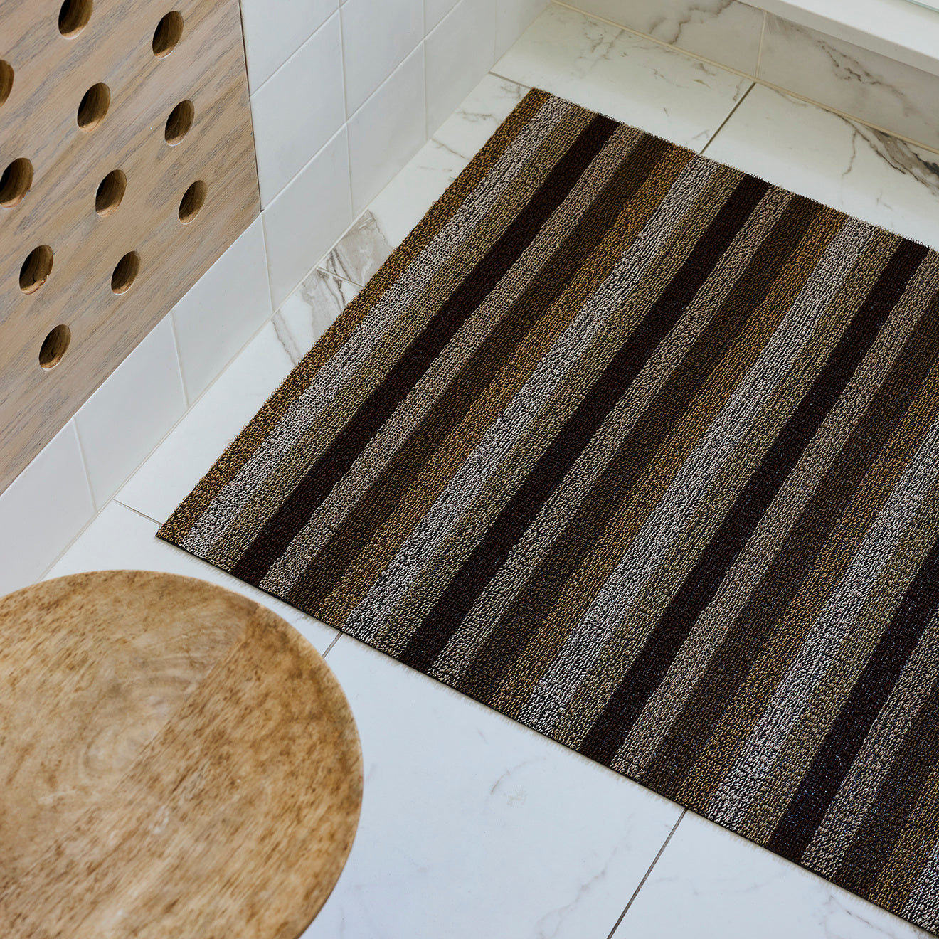 Chilewich striped woven mat with textured terrastrand yarn surface, featuring modern linear design and durable finish.