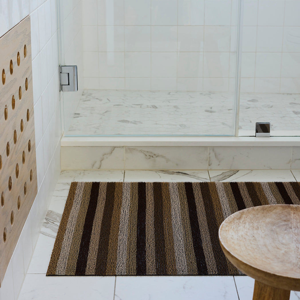 Chilewich striped woven mat with textured terrastrand yarn surface, featuring modern linear design and durable finish.