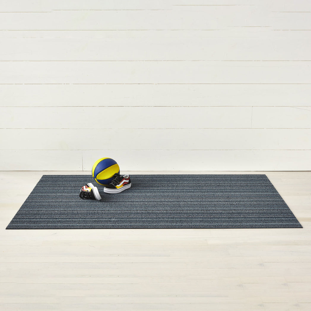 Chilewich striped woven mat with textured terrastrand yarn surface, featuring modern linear design and durable finish.