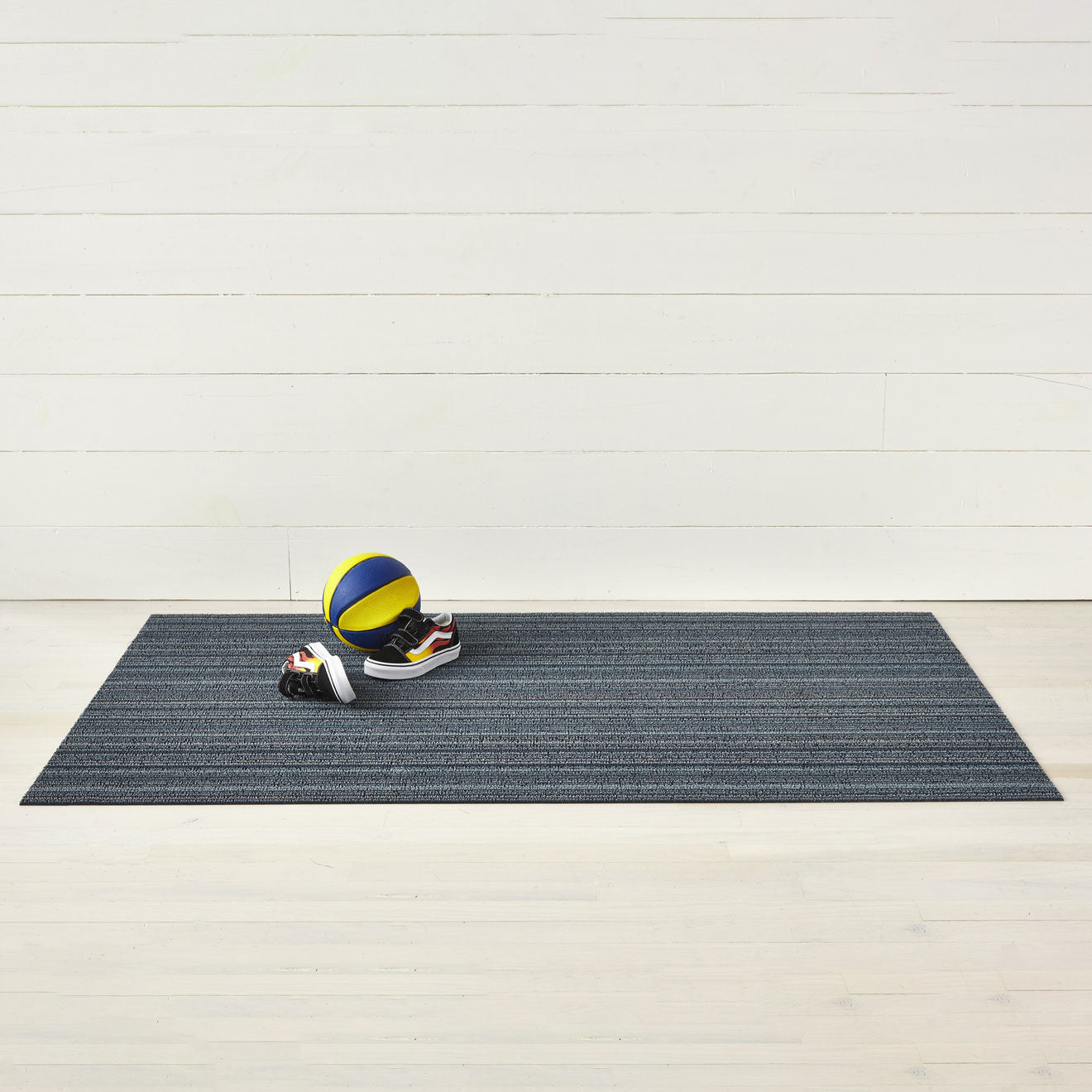 Chilewich striped woven mat with textured terrastrand yarn surface, featuring modern linear design and durable finish.