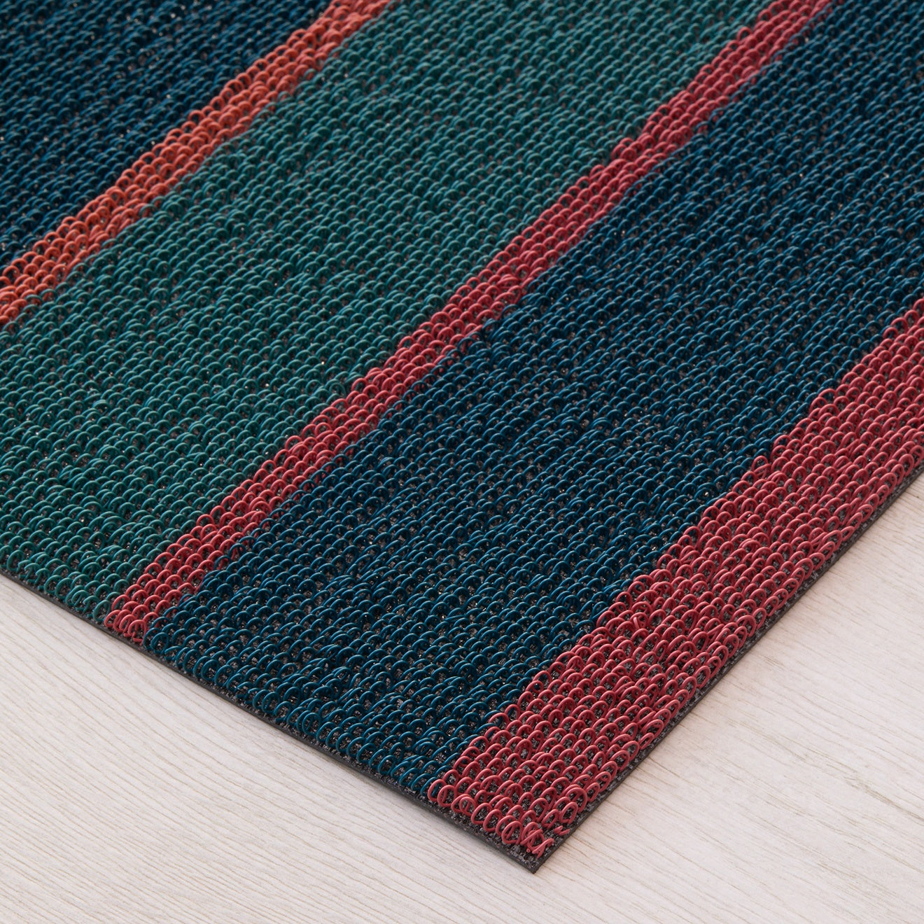 Chilewich striped woven mat with textured terrastrand yarn surface, featuring modern linear design and durable finish.